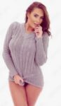 Model posing in a light gray knit sweater against a white background, with one hand near her lips.